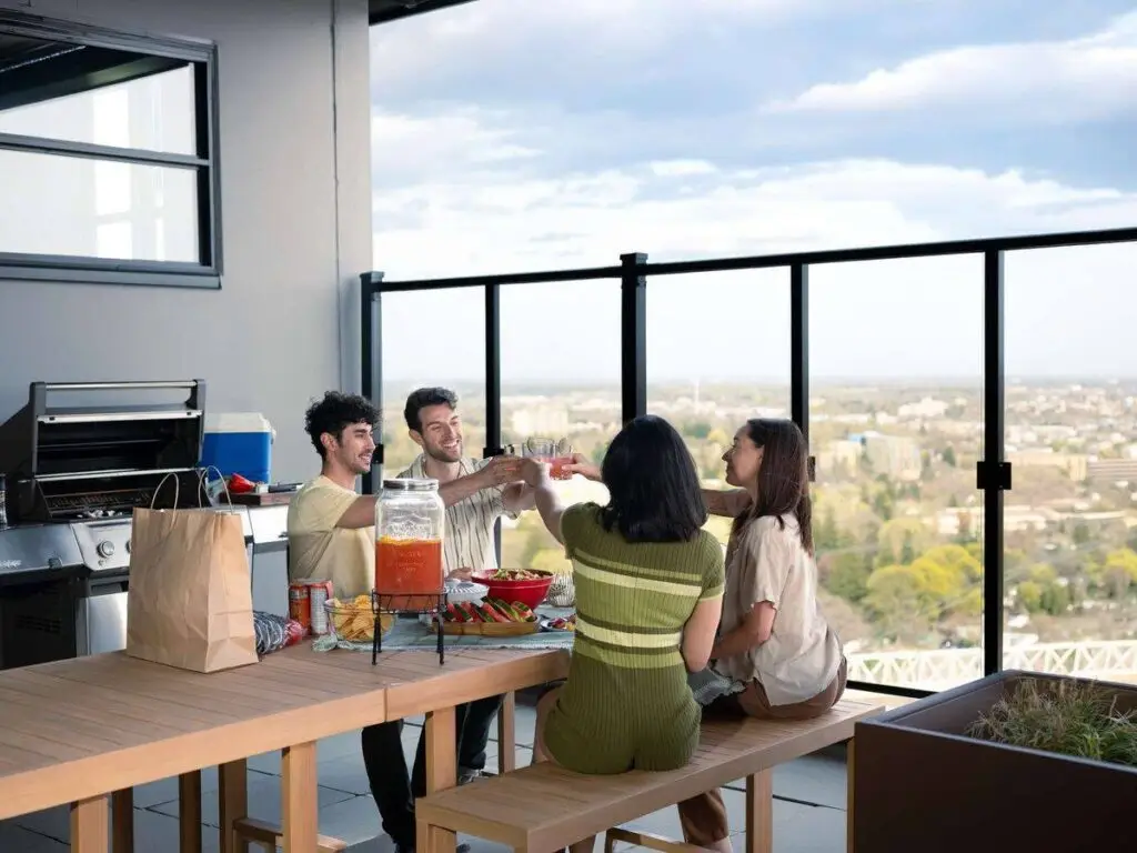 Residents sharing drinks at the rooftop terrace table in front of the BBQs